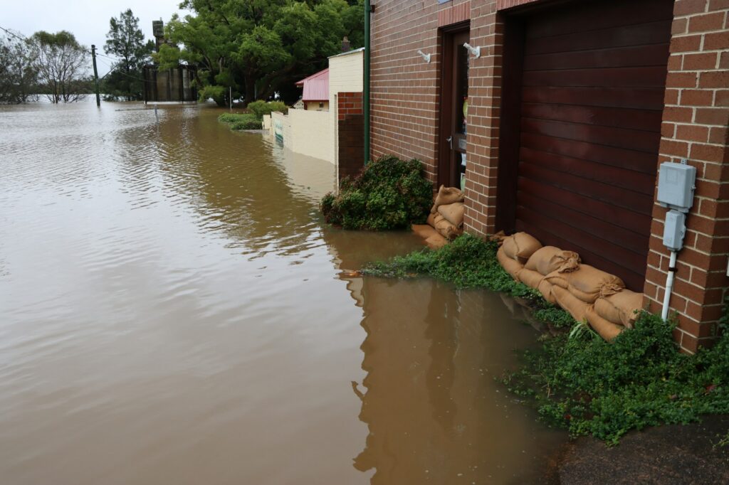 Floodwater and sandbags against a brick building after a storm