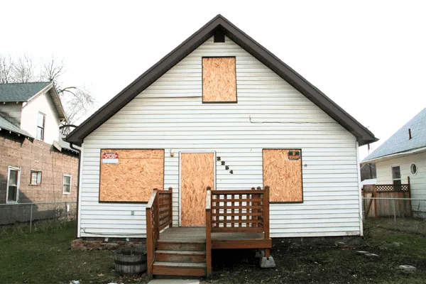 House with plywood emergency board-up over windows and door after damage
